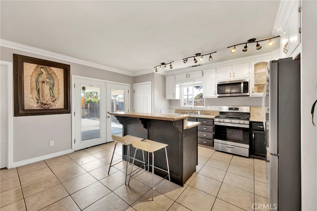 kitchen with appliances with stainless steel finishes, french doors, a kitchen island, crown molding, and white cabinetry