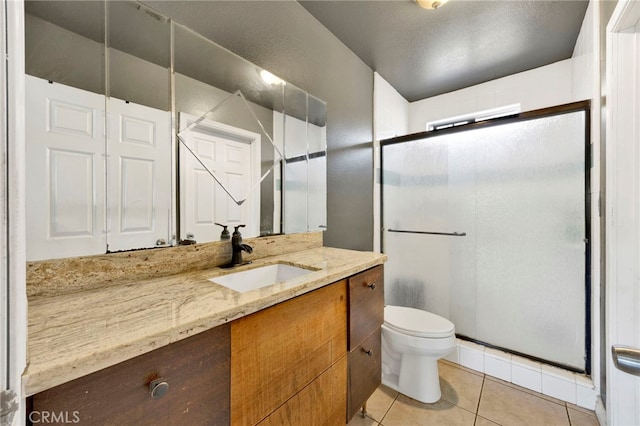 bathroom with tile patterned floors, vanity, a shower with shower door, and toilet