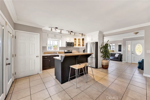 kitchen with a breakfast bar, stainless steel appliances, sink, white cabinets, and a kitchen island