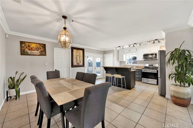 dining area with light tile patterned floors, track lighting, crown molding, and a notable chandelier