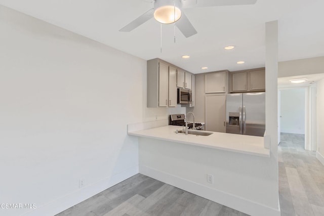 kitchen with sink, light hardwood / wood-style flooring, ceiling fan, gray cabinets, and stainless steel appliances