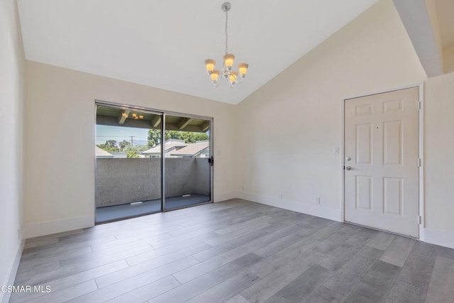 unfurnished room with hardwood / wood-style floors, high vaulted ceiling, and an inviting chandelier