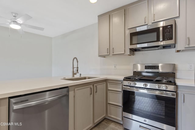 kitchen featuring kitchen peninsula, gray cabinetry, stainless steel appliances, ceiling fan, and sink