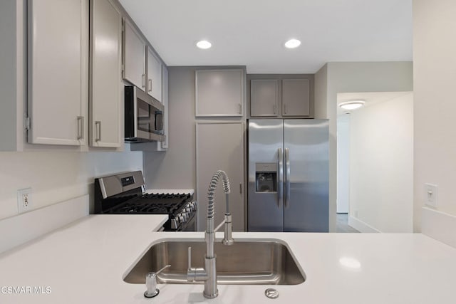 kitchen with stainless steel appliances, gray cabinetry, and sink