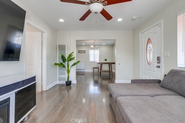 living room featuring wood-type flooring and ceiling fan with notable chandelier