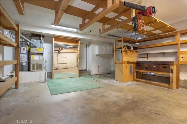 basement featuring secured water heater, heating unit, and a workshop area