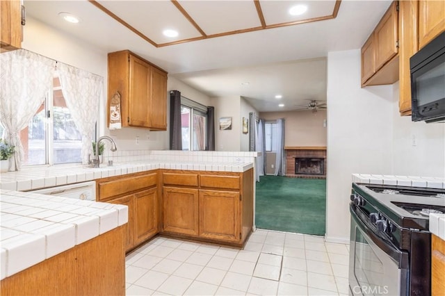 kitchen featuring tile countertops, black appliances, sink, light tile patterned floors, and kitchen peninsula