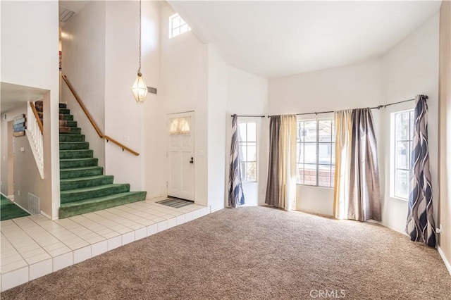 carpeted entrance foyer featuring plenty of natural light and a high ceiling