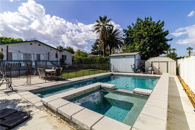 view of pool featuring an in ground hot tub, a shed, and a patio area