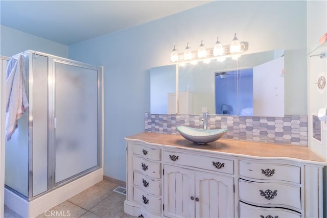 bathroom featuring backsplash, tile patterned floors, a shower with door, and vanity