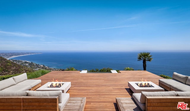 wooden deck with a water view and an outdoor living space with a fire pit