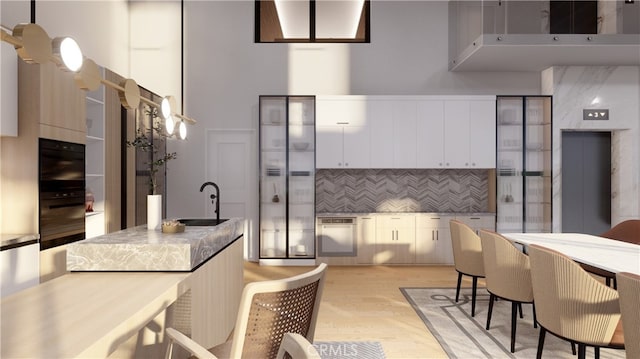 kitchen featuring sink, decorative light fixtures, white cabinets, light hardwood / wood-style floors, and tasteful backsplash