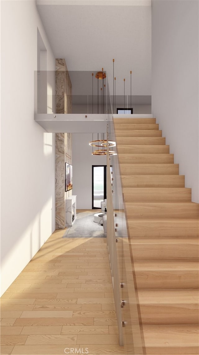 stairway with wood-type flooring and a chandelier