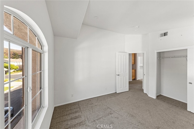 unfurnished bedroom featuring a closet, carpet, and vaulted ceiling