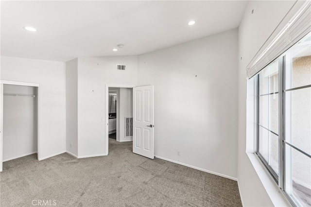 unfurnished bedroom with vaulted ceiling, light carpet, and a closet