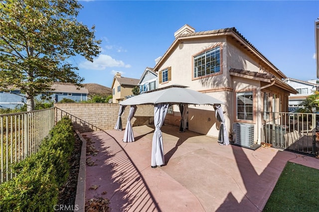 rear view of property featuring a gazebo, central air condition unit, and a patio