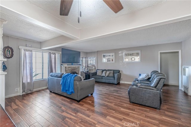 living room with ceiling fan, a stone fireplace, and a textured ceiling