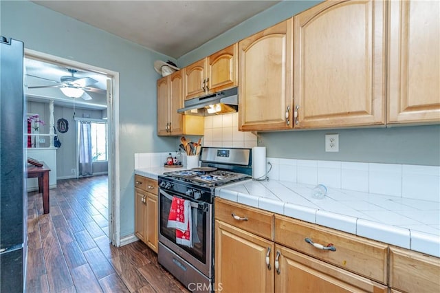 kitchen with ceiling fan, backsplash, stainless steel gas range, and tile counters