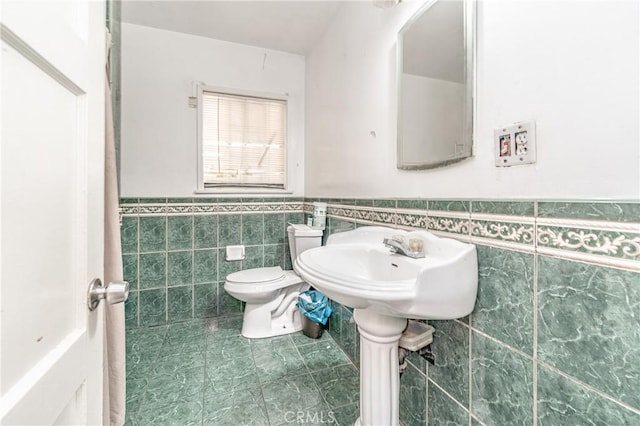 bathroom featuring toilet, tile patterned flooring, and tile walls