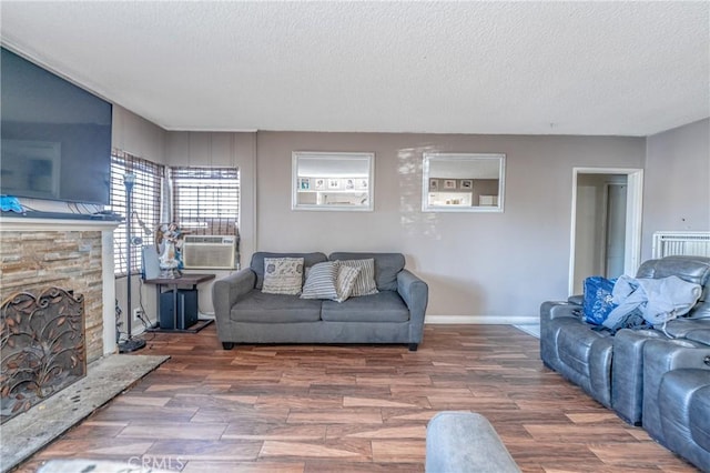 living room featuring a textured ceiling, cooling unit, and a fireplace