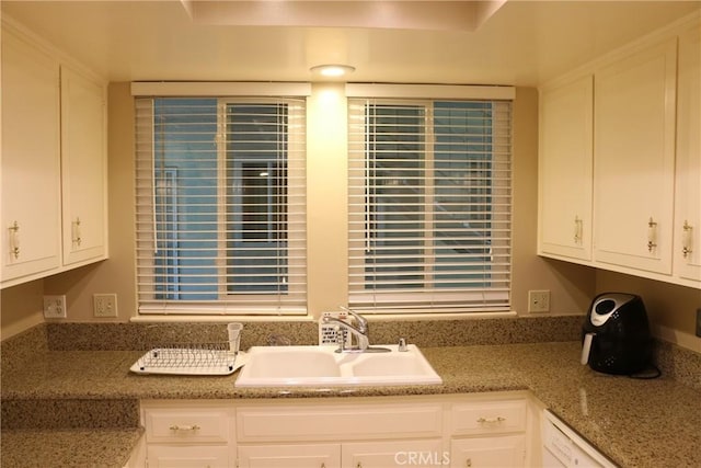 kitchen with white cabinets, white dishwasher, stone counters, and sink