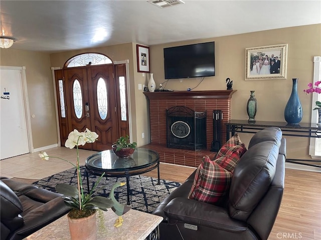 living room with a brick fireplace and light hardwood / wood-style floors