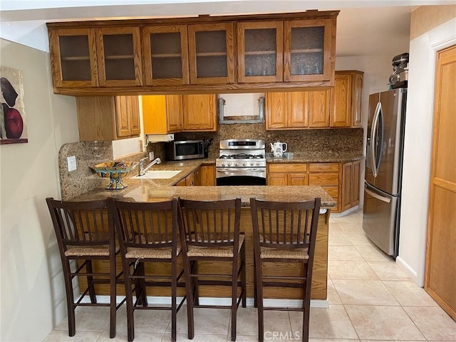 kitchen with sink, stainless steel appliances, a kitchen breakfast bar, tasteful backsplash, and kitchen peninsula