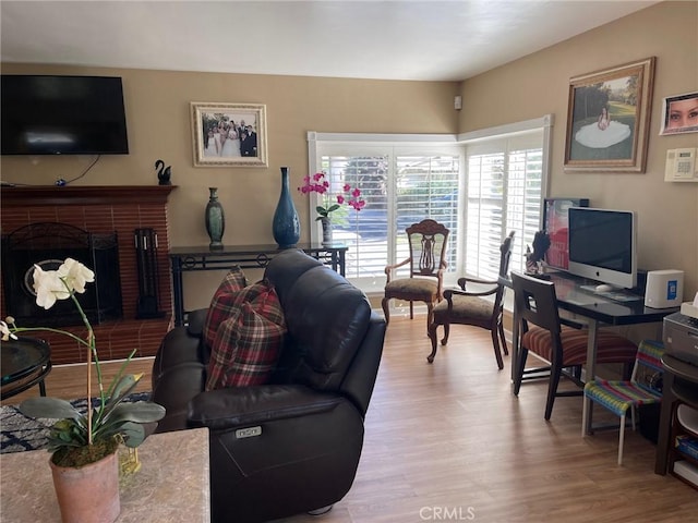 living room featuring a brick fireplace and light wood-type flooring