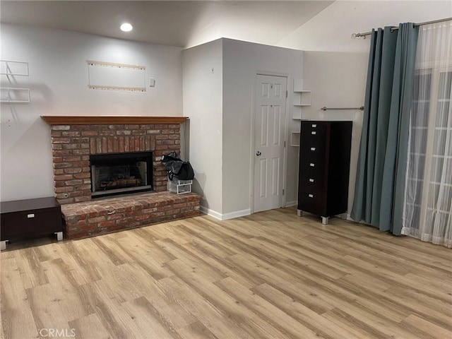 unfurnished living room with a brick fireplace and light wood-type flooring