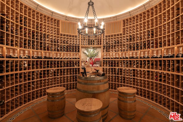 wine area with tile patterned floors and a notable chandelier