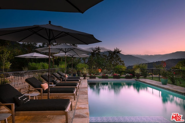 pool at dusk featuring a patio area and a mountain view