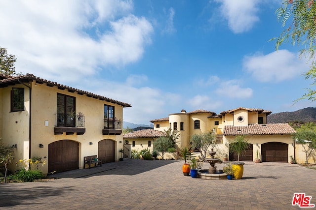 mediterranean / spanish-style house featuring a mountain view, a garage, and a balcony