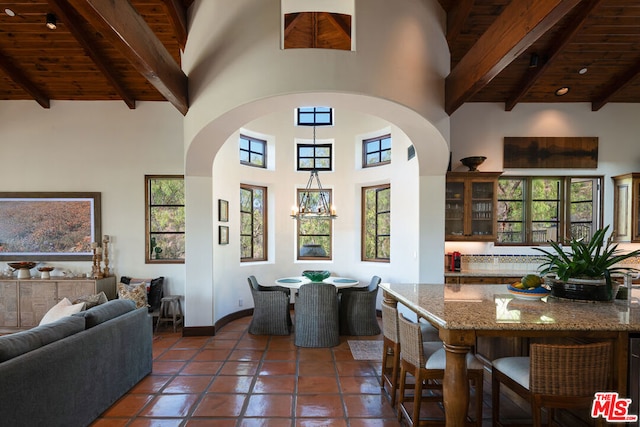 tiled dining room featuring wood ceiling, a towering ceiling, and beamed ceiling