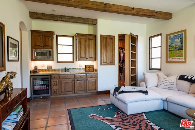 tiled living room with beamed ceiling, plenty of natural light, wet bar, and beverage cooler