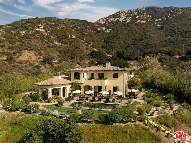 back of property featuring a patio area, a mountain view, and a balcony