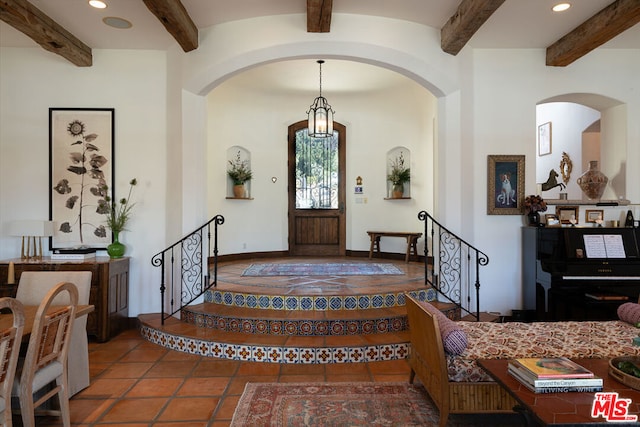 tiled entrance foyer featuring beamed ceiling