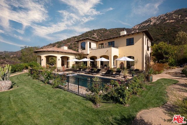 rear view of house with a yard, a patio, and a mountain view