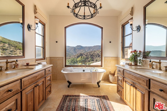 bathroom with a bathing tub, a mountain view, vanity, and tile walls