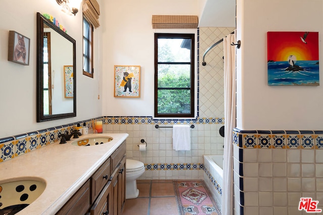 bathroom with a tub, tile walls, toilet, vanity, and tile patterned flooring