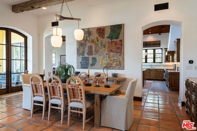 tiled dining space with beamed ceiling and a high ceiling