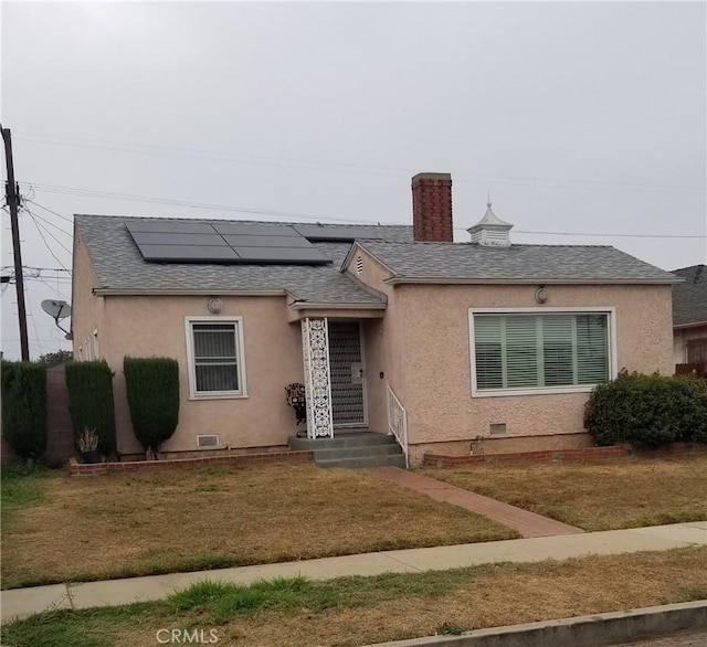 view of front of home featuring solar panels and a front yard