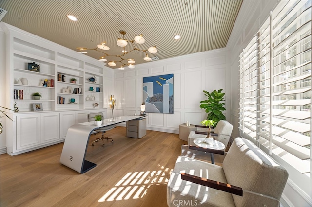 office featuring built in shelves, crown molding, light hardwood / wood-style flooring, and a notable chandelier