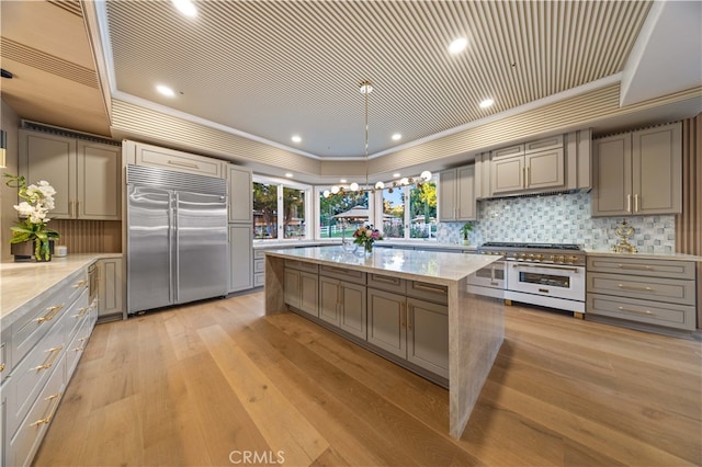 kitchen with gray cabinets, light hardwood / wood-style floors, high end appliances, and crown molding