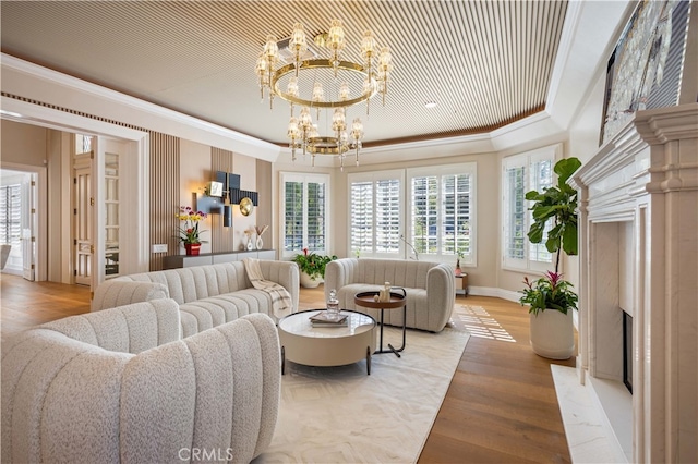 living room with a raised ceiling, crown molding, light hardwood / wood-style flooring, and an inviting chandelier