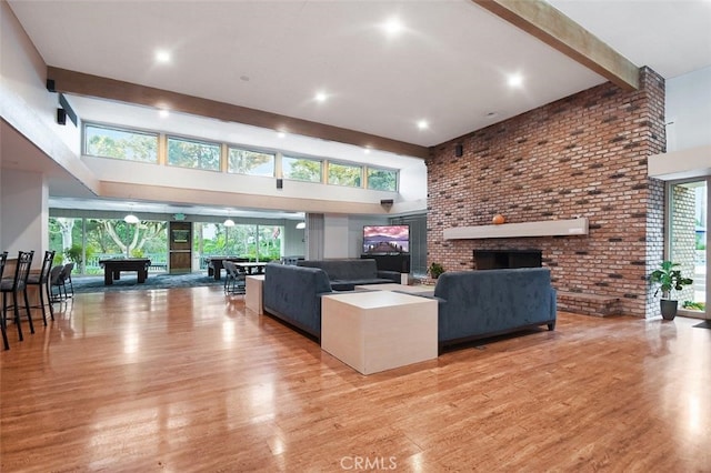 living room with beam ceiling, light hardwood / wood-style floors, and a high ceiling