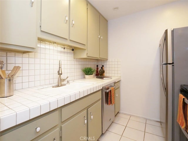 kitchen with tile countertops, sink, light tile patterned floors, tasteful backsplash, and stainless steel appliances