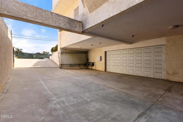 view of side of property with fence, a garage, driveway, and stucco siding