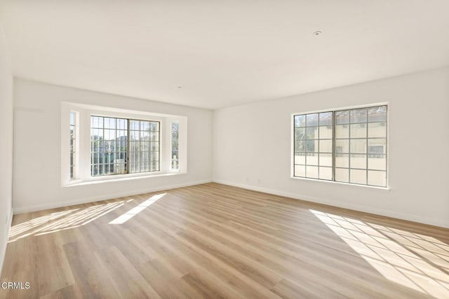 spare room with light wood-type flooring and baseboards