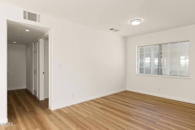 empty room with light wood-style flooring, baseboards, and visible vents