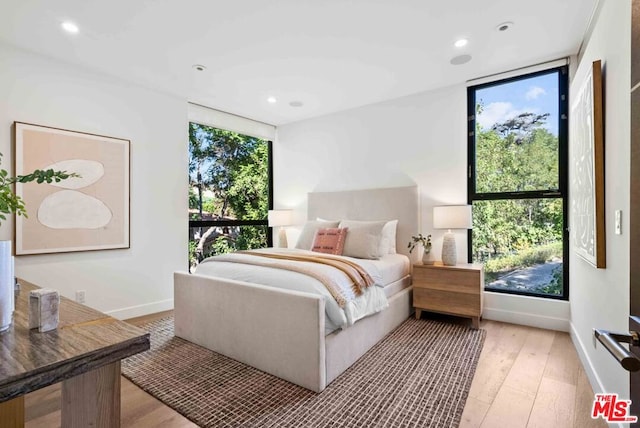 bedroom with multiple windows and light hardwood / wood-style flooring